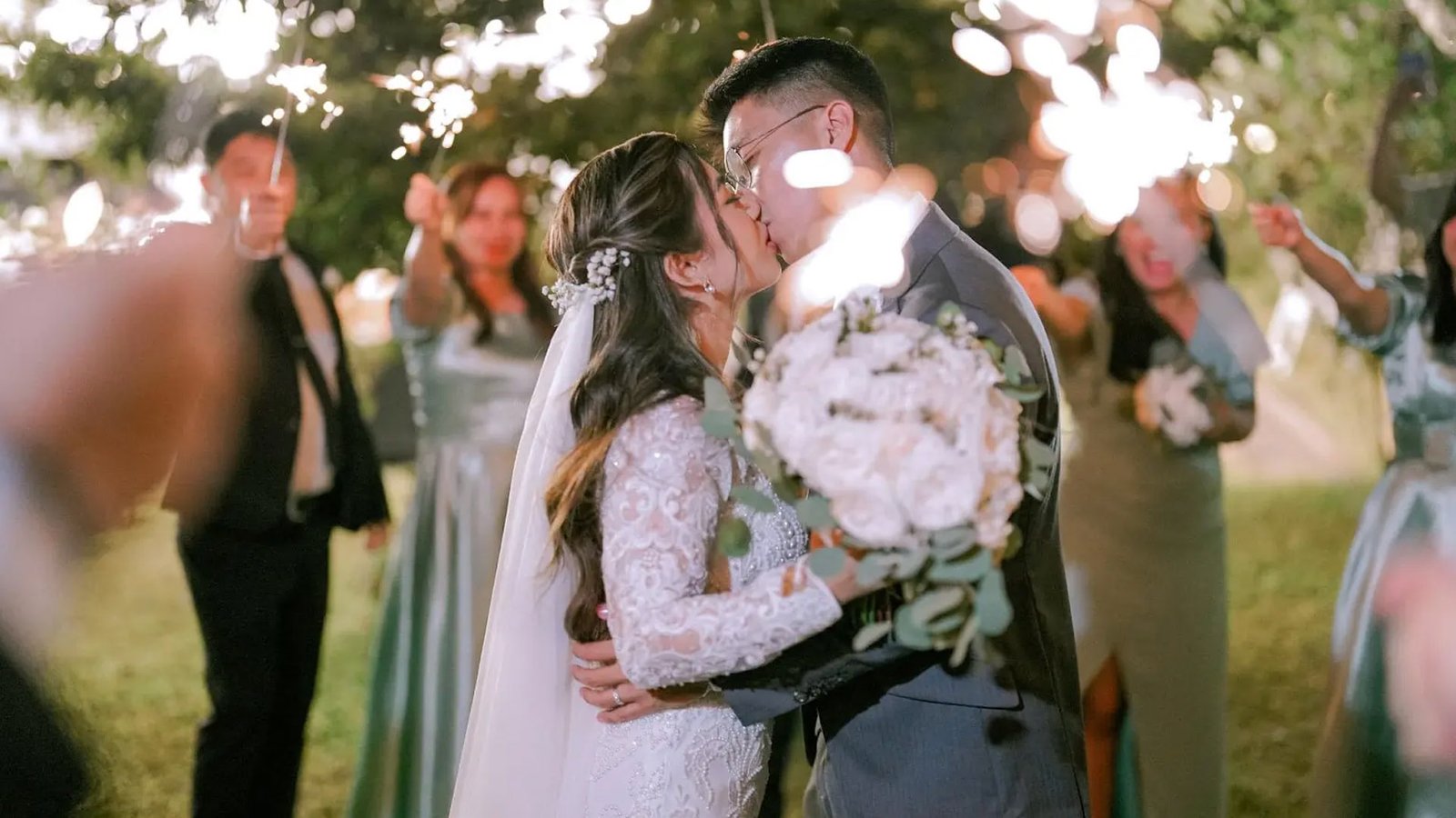 Tagaytay wedding at Savanna Farm: bride and groom kiss during sparkler send-off in a garden